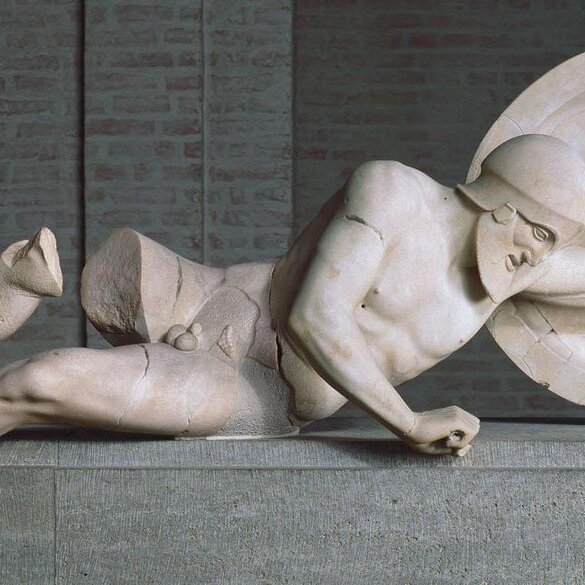 The Fallen Warrior statue is believed to show a casualty of the Trojan War. The subject is shown suffering on the ground. Even with physical damage, you can see pain and anguish on the subject’s face. The soldier is holding onto a large shield and is wearing head armor.
The statue was found in the Temple of Aphaia, which is on the island of Aegina. It was removed and sold to royalty following its discovery. Today, it’s on display in Munich, Germany.

